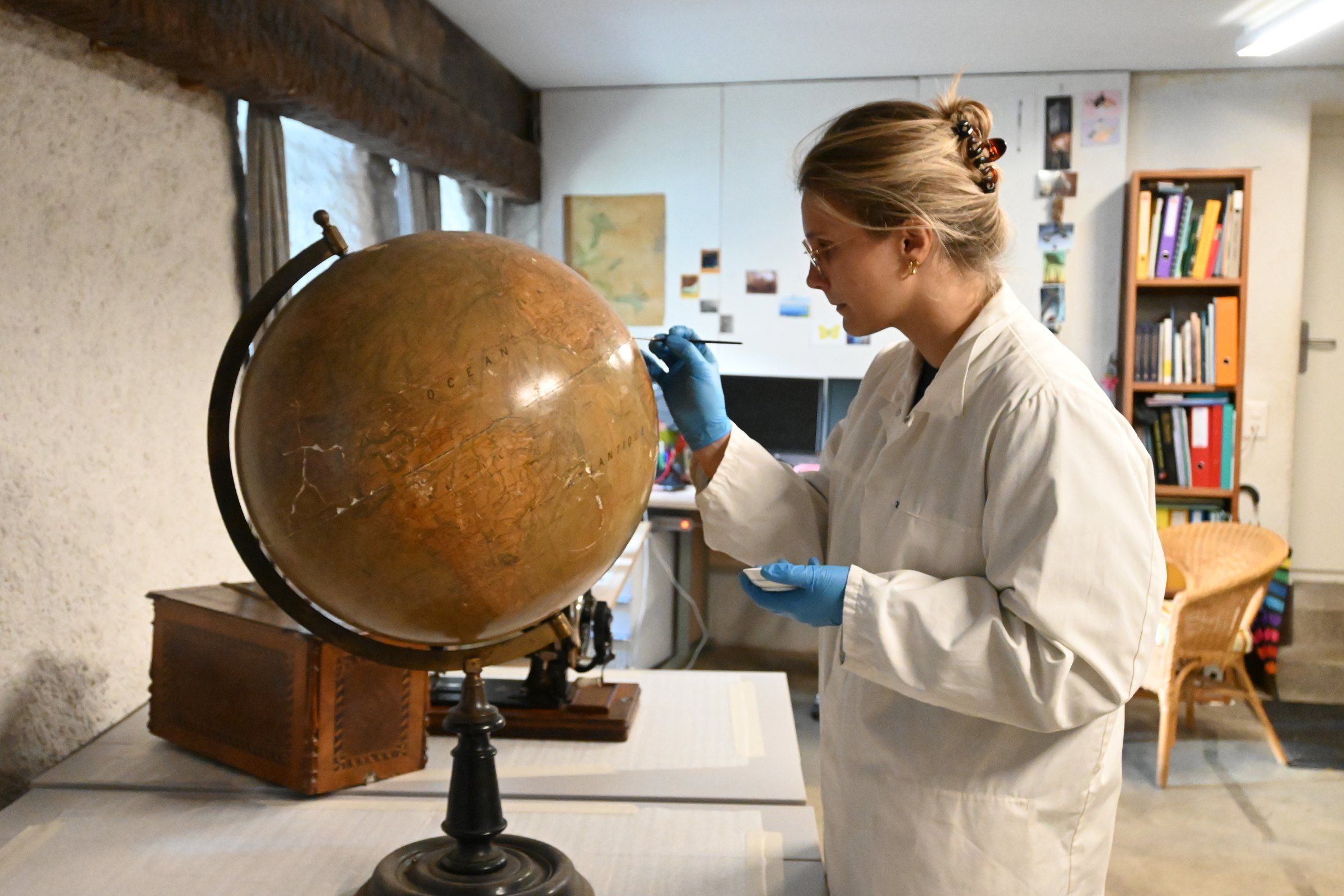 Mathilde Sneiders examinant un globe terrestre ancien dans son atelier