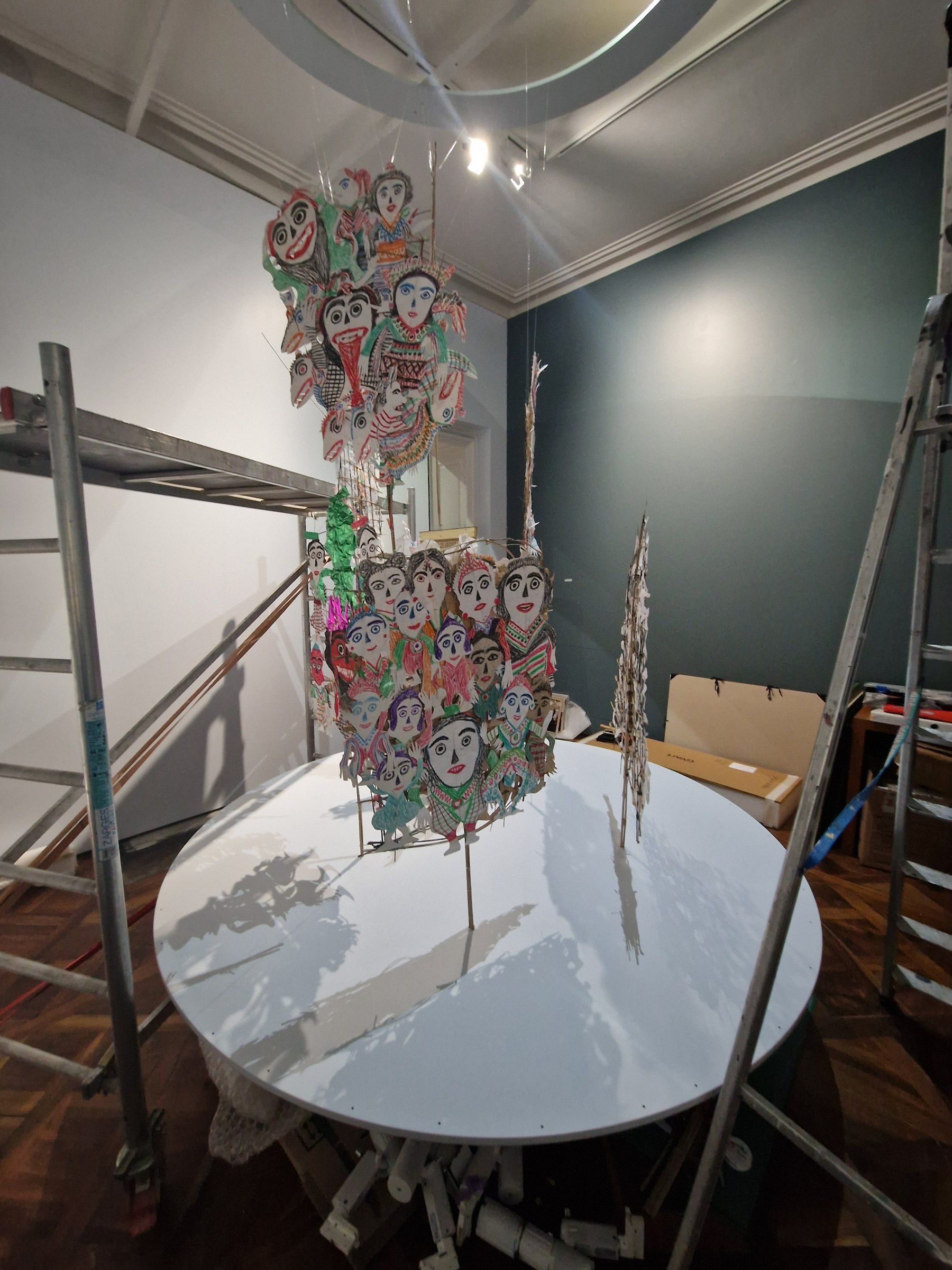 Œuvre suspendue au-dessus d’un socle circulaire pendant le montage de l’exposition